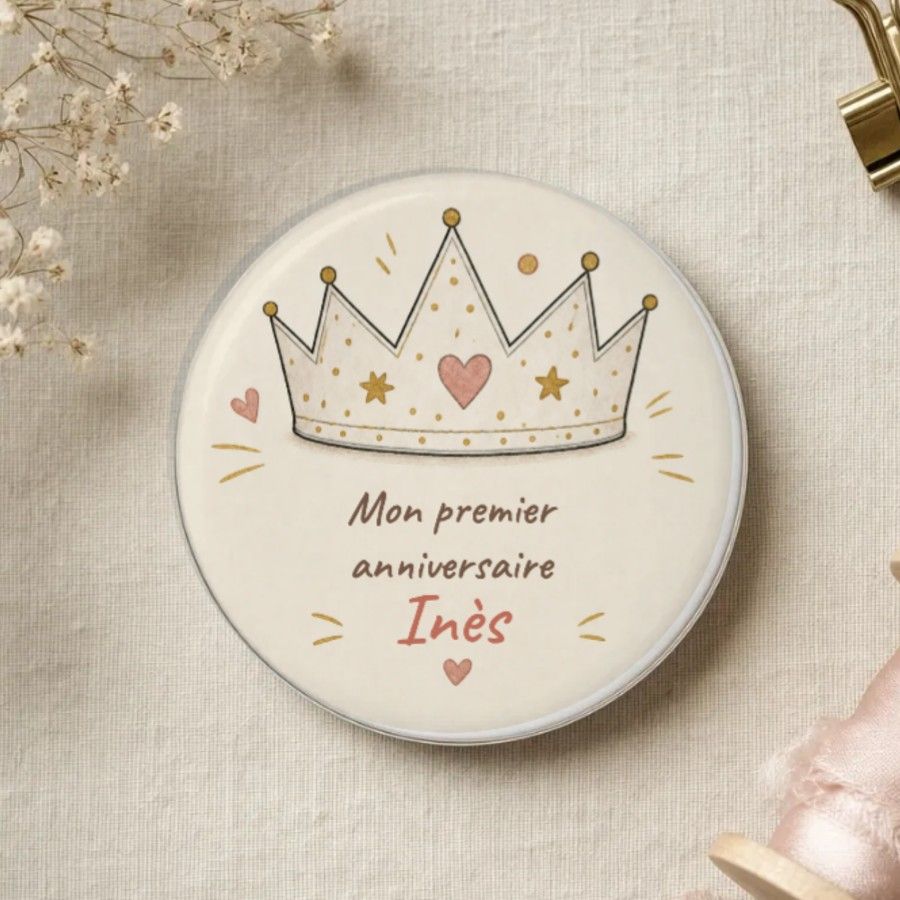 Magnet rond : une couronne de fête dessinée au trait avec des étoiles dorées